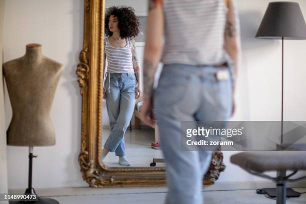 reflection of young tattooed woman in the mirror - skinny trousers stock pictures, royalty-free photos & images