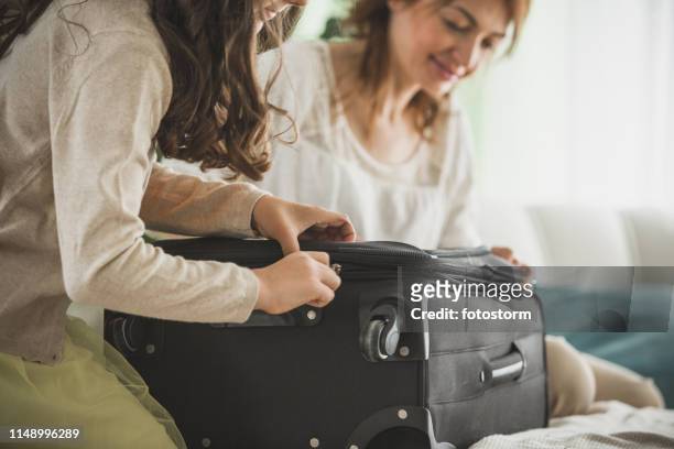 teamwork on closing a suitcase - teen packing suitcase stock pictures, royalty-free photos & images