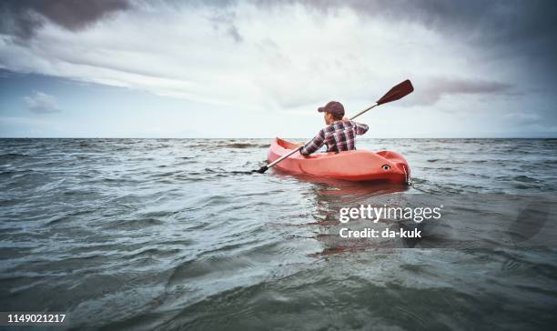 teenage boy canoeing at sunset - rowboat stock pictures, royalty-free photos & images