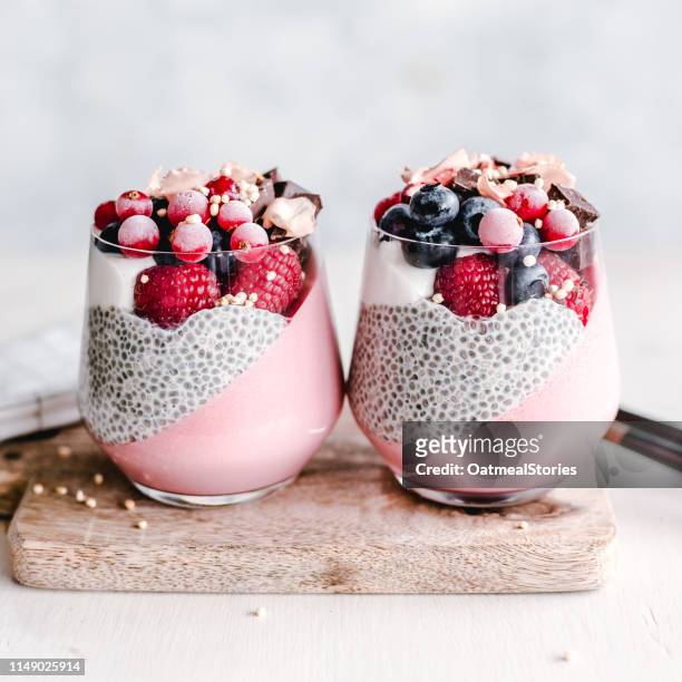 two chia and panna cotta desserts with raspberries, blueberries and redcurrants - chiasamen stock-fotos und bilder
