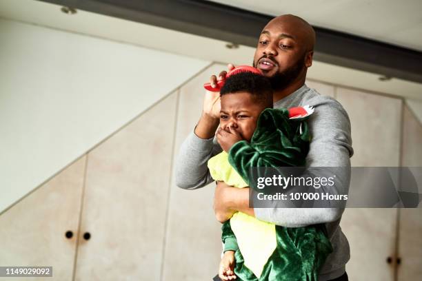 father struggling to brush son's hair - stressed parent stock pictures, royalty-free photos & images