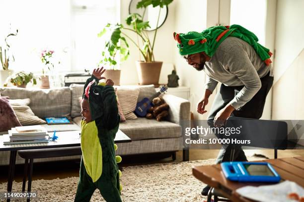 father and son dressed as dragons playing in living room - erwachsene person stock-fotos und bilder