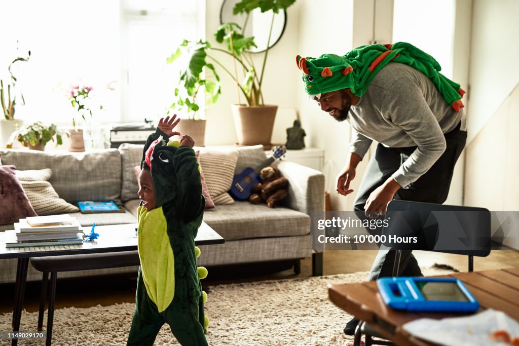 Father and son dressed as dragons playing in living room