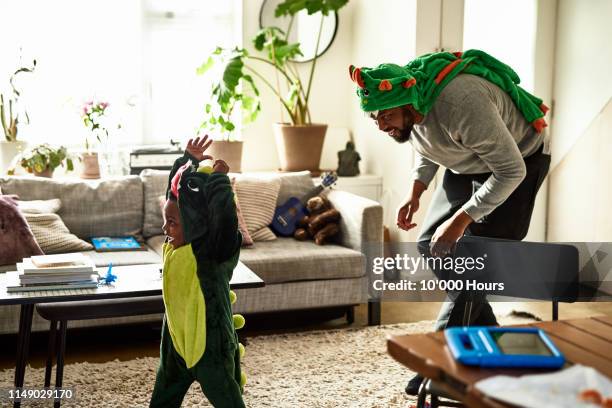 father and son dressed as dragons playing in living room - family fun stock pictures, royalty-free photos & images