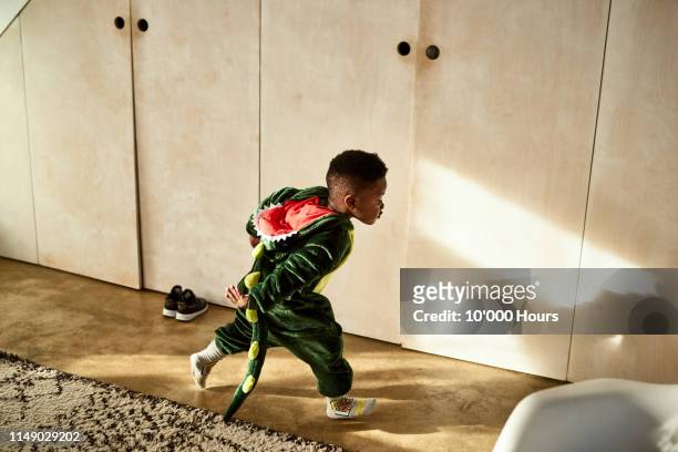 toddler running through house in dragon costume - child playing dress up stock-fotos und bilder