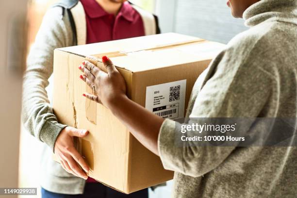 cropped image of woman receiving delivery at front door - passing giving stock pictures, royalty-free photos & images