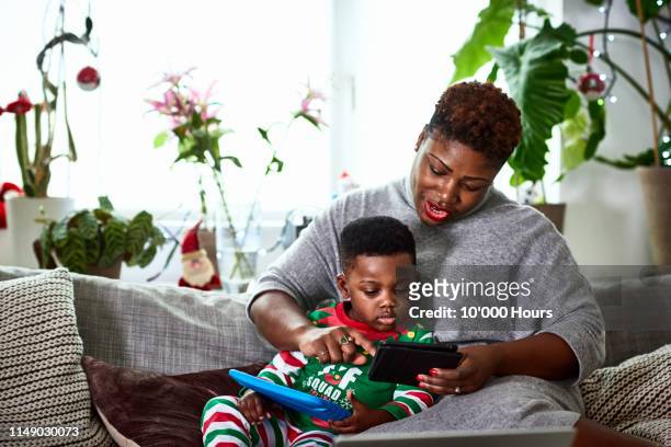 Mother with arm around son using digital tablet