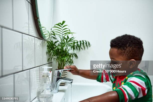independent toddler washing hands alone at sink - 10 off stock-fotos und bilder