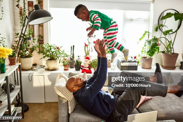 Father throwing and catching toddler on sofa