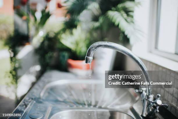 leaking chrome tap in a kitchen - abfluss stock-fotos und bilder