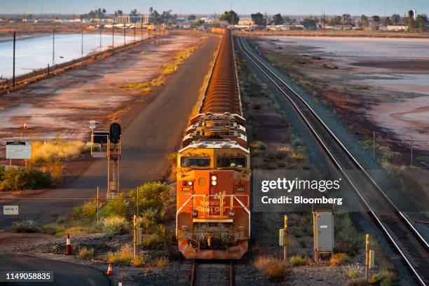 Billiton Ltd. Freight train carrying iron ore travels along a rail track towards Port Hedland, Australia, on Tuesday, March 19, 2019. A two-day drive...