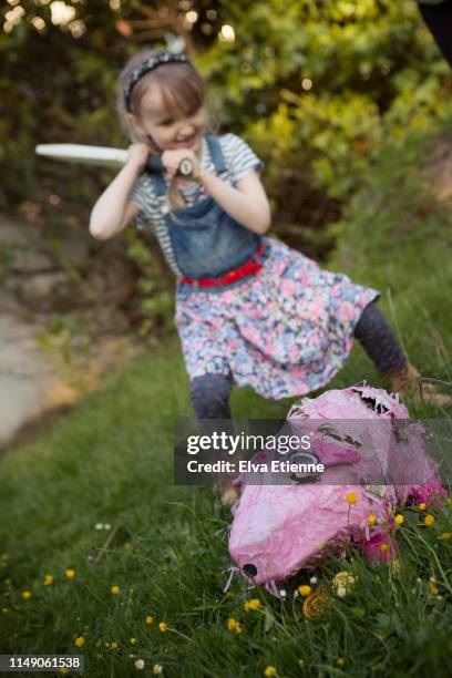 girl (6-7) with determined expression about to hit a pink pig pinata with a sports bat - bouton d'or photos et images de collection