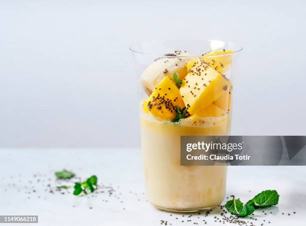 a glass of banana and mango smoothie on white background - mango smoothie stock pictures, royalty-free photos & images