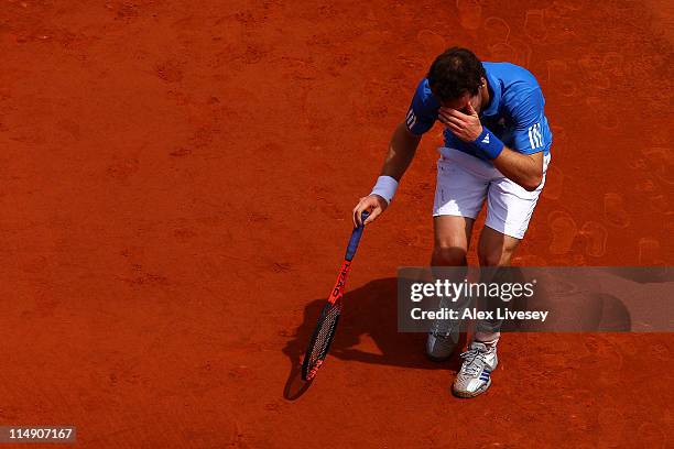 Andy Murray of Great Britain holds his hand to his face after injuring his foot during the men's singles round three match between Andy Murray of...