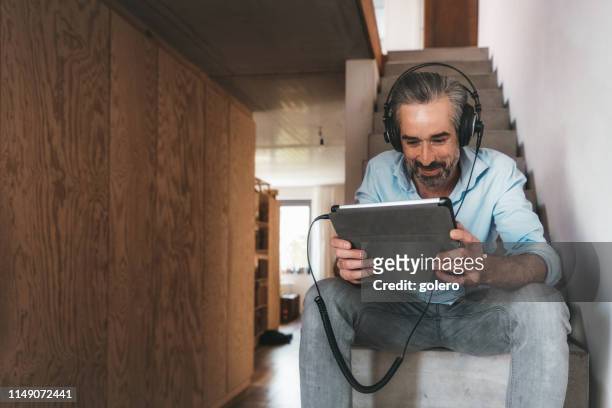 glücklicher mann mit kopfhörer und tablet auf betontreppe - ipad kopfhörer stock-fotos und bilder