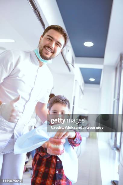 dentist encouraging kid to play with prosthetic teeth - pediatric dentistry stock pictures, royalty-free photos & images