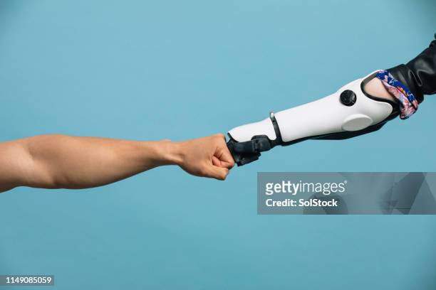 ein menschlicher und robotischer arm, der einen faustschlag macht - menschlicher arm stock-fotos und bilder
