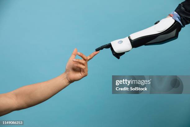 human and robotic hand touching - robot arm human arm stock pictures, royalty-free photos & images