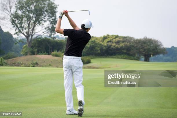 rear view of man teeing off on golf course - golf swing stock pictures, royalty-free photos & images