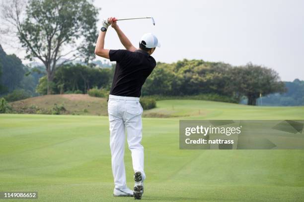 rear view of man teeing off on golf course - golfer swing stock pictures, royalty-free photos & images