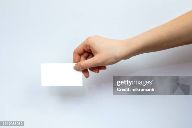 hand holding out a business card - hand holding card stock-fotos und bilder