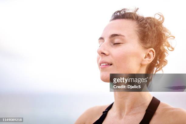 relaxed young woman meditating outdoors by the sea head close up. - breathing imagens e fotografias de stock