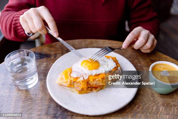 man eating croque madame sandwich with cheese and fried egg - breakfast eggs stockfoto's en -beelden