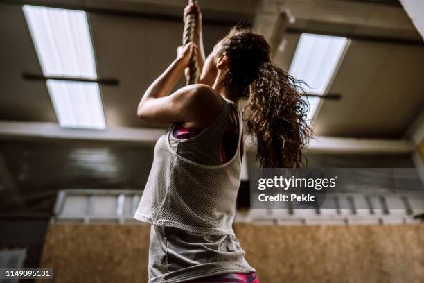 athlete women exercising on climbing rope in gym - sports training drill stock pictures, royalty-free photos & images