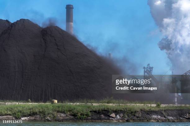 coal dust from steel mill blowing into detroit river, michigan - coal wind stockfoto's en -beelden