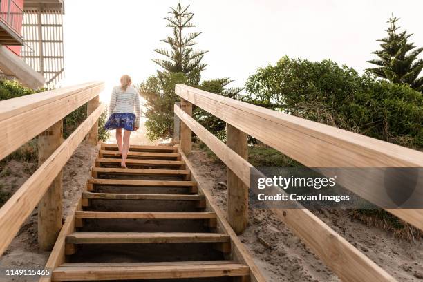 blonde haired girl walking up wooden stairs at beach - girl rising stock pictures, royalty-free photos & images