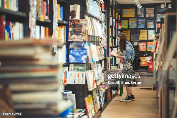 étudiant féminin recherchant des livres dans la librairie (couvertures de livre sont édités) - librairie photos et images de collection