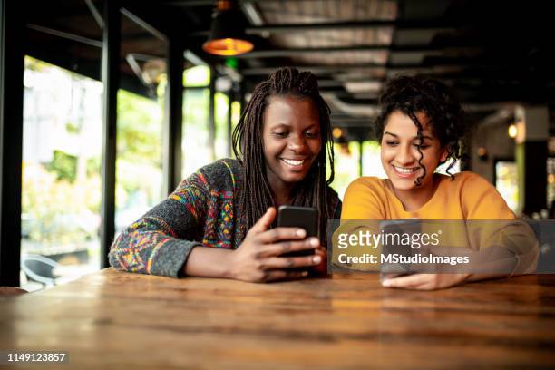 dos amigos milleniales usando el teléfono móvil. - enviar actividad fotografías e imágenes de stock