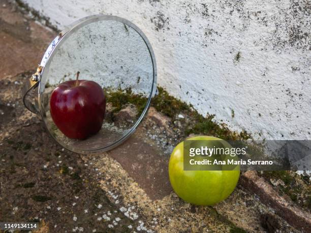 a green apple reflected in a mirror as a red apple. diversity concept - distorted body image stock pictures, royalty-free photos & images