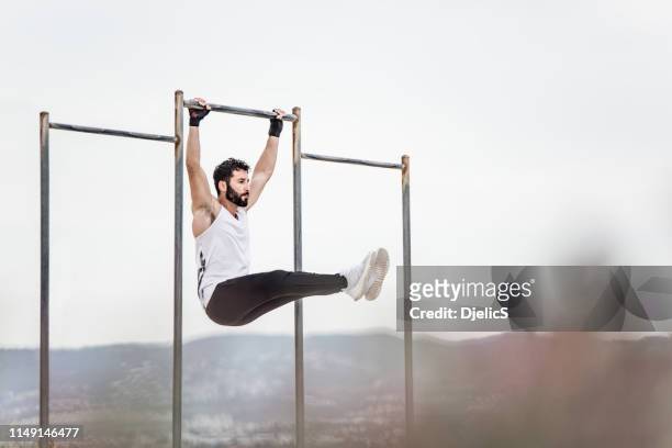 young athletic man doing an ab workout and pull ups. - hanging stock pictures, royalty-free photos & images