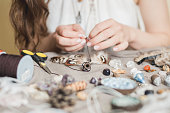 Woman hands making handmade gemstone jewelry, home workshop. Woman artisan creates jewelry. Art, hobby, handcraft concept