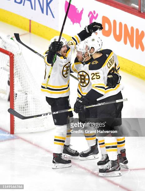 Chris Wagner of the Boston Bruins celebrates with Brandon Carlo and Joakim Nordstrom after scoring a goal on Curtis McElhinney of the Carolina...