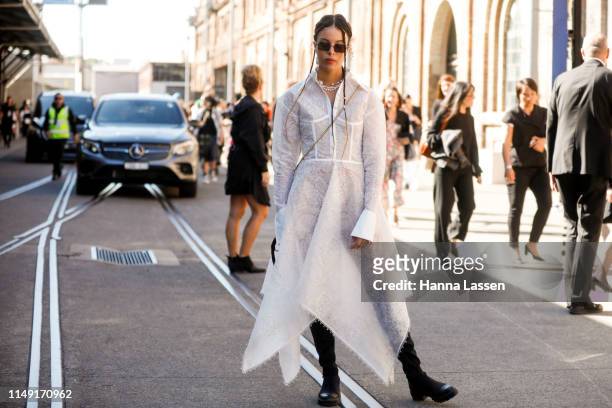 Fleur Egan wearing Leo and Lin white lace dress and black knee high boots at Mercedes-Benz Fashion Week Resort 20 Collections on May 15, 2019 in...