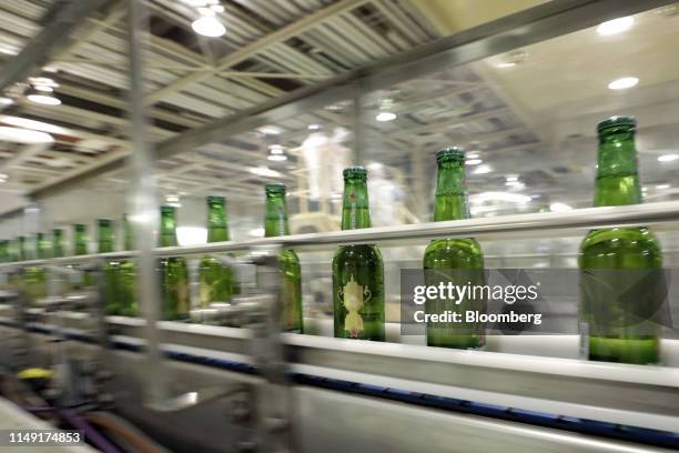 Bottles of Heineken NV brand beer, featuring labels with the Web Ellis Cup logo, move along the production line of a Kirin Brewery Co. Factory in...