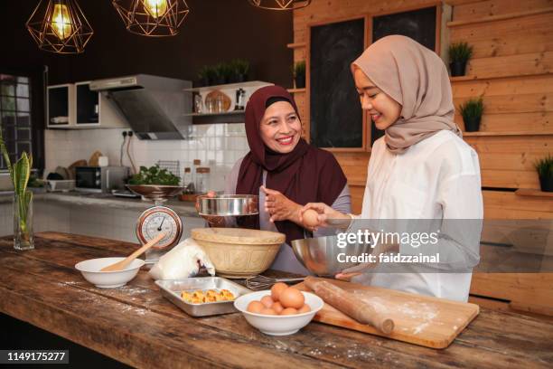 a malay muslim family of mother and daughter baking for hari raya aidilfitri/ eid-ul-fitr - mother daughter baking stock pictures, royalty-free photos & images