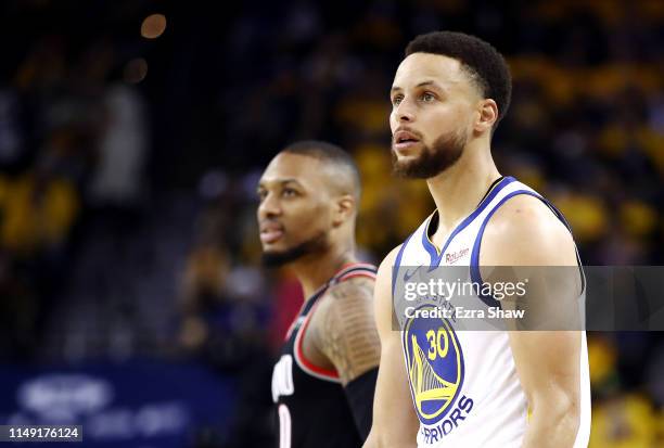 Damian Lillard of the Portland Trail Blazers and Stephen Curry of the Golden State Warriors look on during the second half in game one of the NBA...