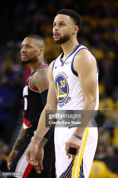 Damian Lillard of the Portland Trail Blazers and Stephen Curry of the Golden State Warriors look on during the second half in game one of the NBA...