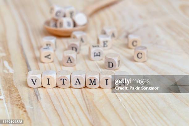 close up vitamin word made from wooden letters on the table and a b c d e on the table background, health concept - lettera a c foto e immagini stock