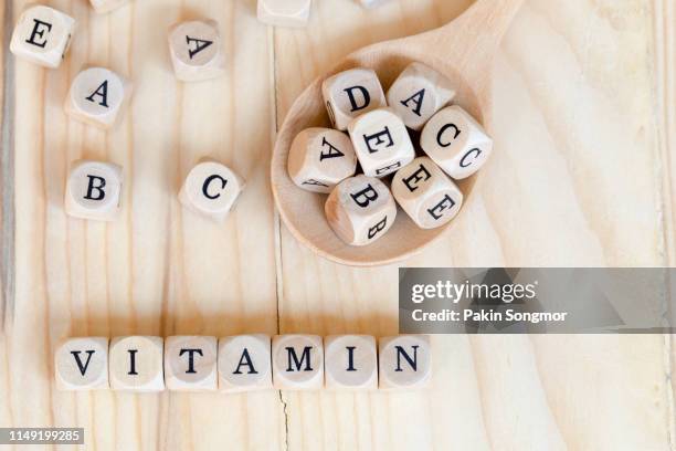 top views vitamin word made from wooden letters on the table and a b c d e on the wood spoon, health concept - lettera a c foto e immagini stock