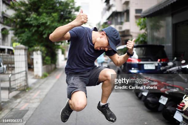 chinese man jumping for joy in the street - ecstatic expression stock pictures, royalty-free photos & images