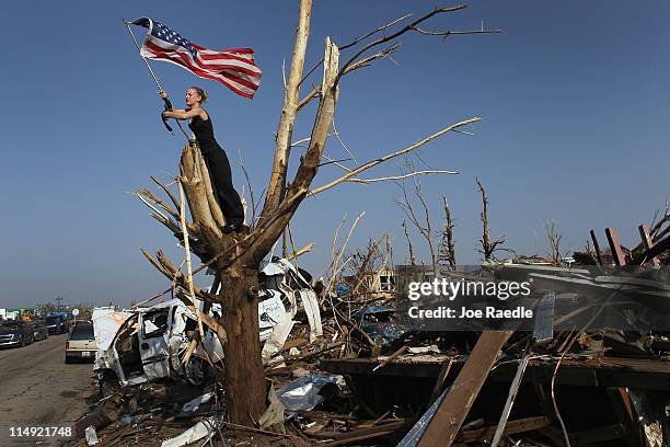 Katlyn Wilkins and Andrea Wilkins Morelli work on securing an American flag in a tree as they deal with the destruction caused by a massive tornado...