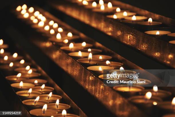 close-up of illuminated tea lights in dark - cattolicesimo foto e immagini stock