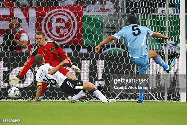 Walter Gargano of Uruguay scores his team's first goal against Philipp Lahm and goalkeeper Manuel Neuer of Germany during the international friendly...