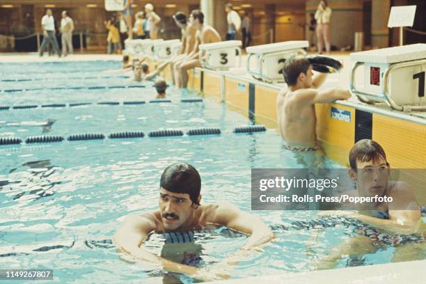 American swimmer Mark Spitz pictured in the pool with two fellow United States swimming team members during competition in a swimming relay event at...