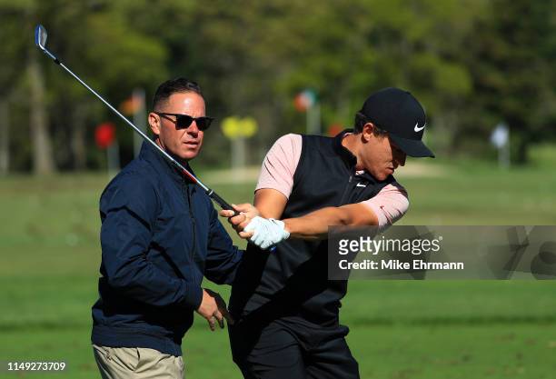 Cameron Champ of the United States plays a shot on the practice range as golf instructor Sean Foley looks on during a practice round prior to the...