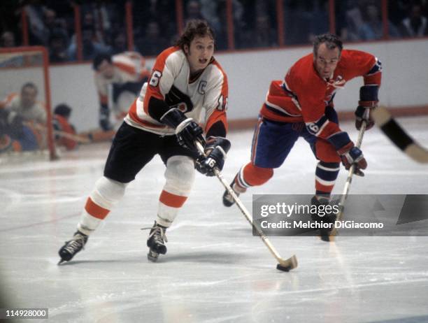 Bobby Clarke of the Philadelphia Flyers skates with the puck as Henri Richard of the Montreal Canadiens follows behind during their game circa 1973...